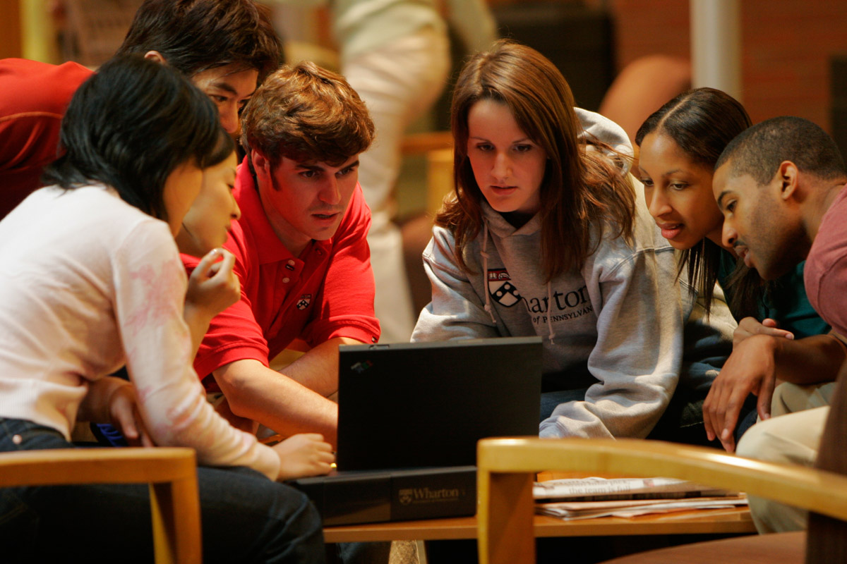 A group of students working in a group and looking at a laptop screen.