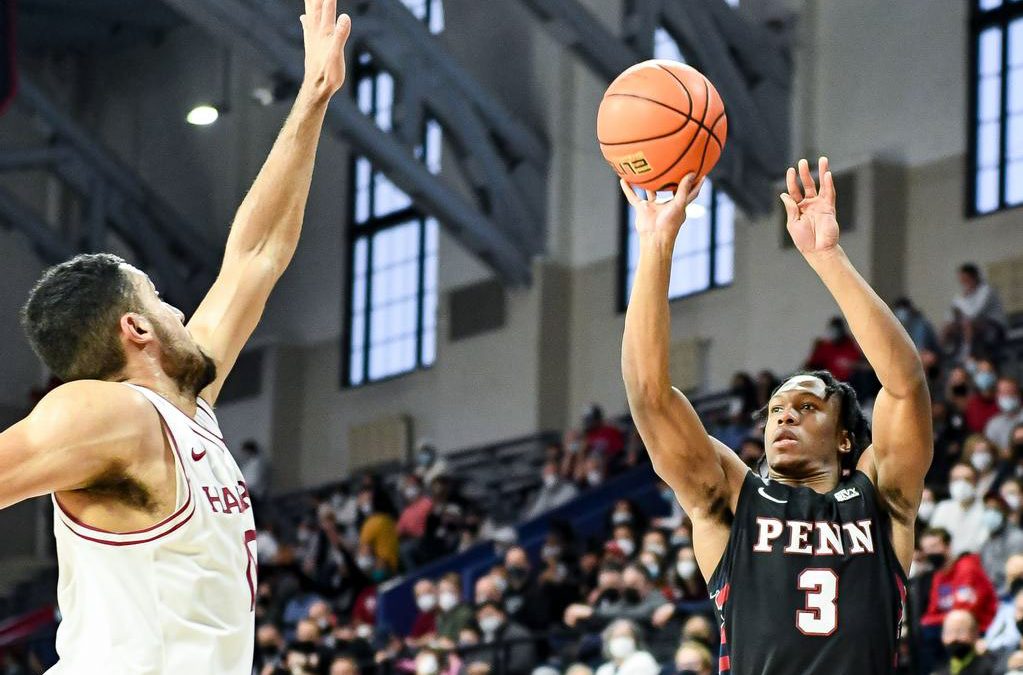 A Penn basketball player prepares to make a shot over a defender during a game.