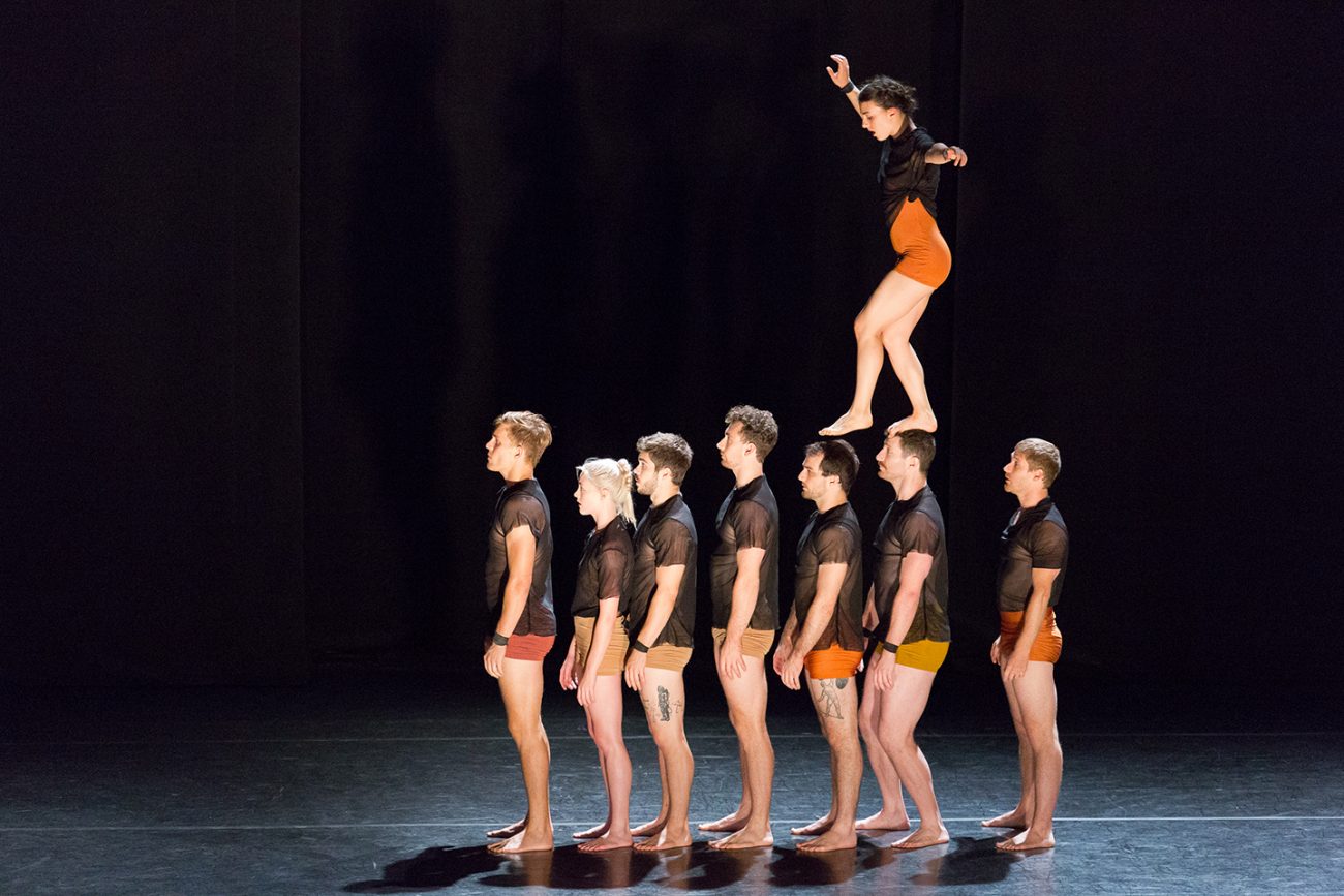 woman walking on performers heads who are standing up
