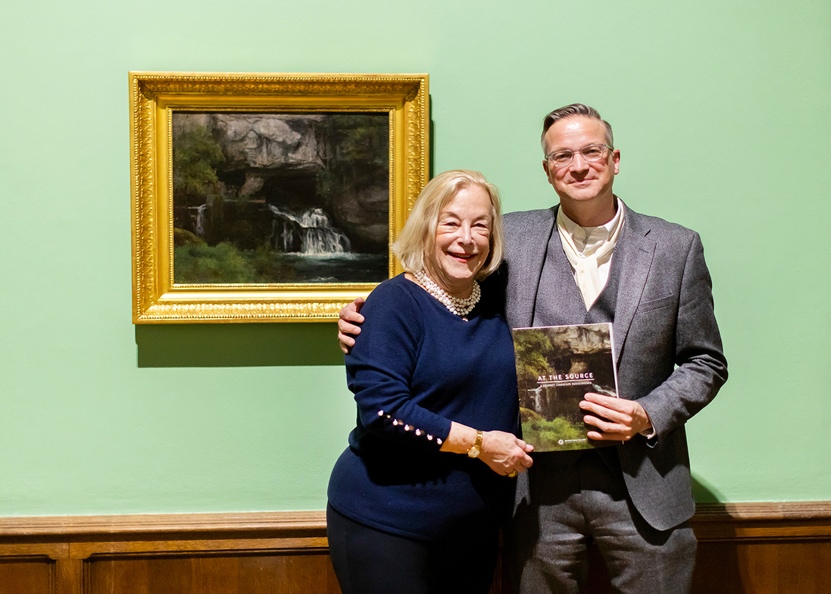 Betsy Scott Kleebatt and Andre Dombrowski stand together beside “La Source du Lison” by Gustave Courbet in the Arthur Ross Gallery at the University of Pennsylvania.