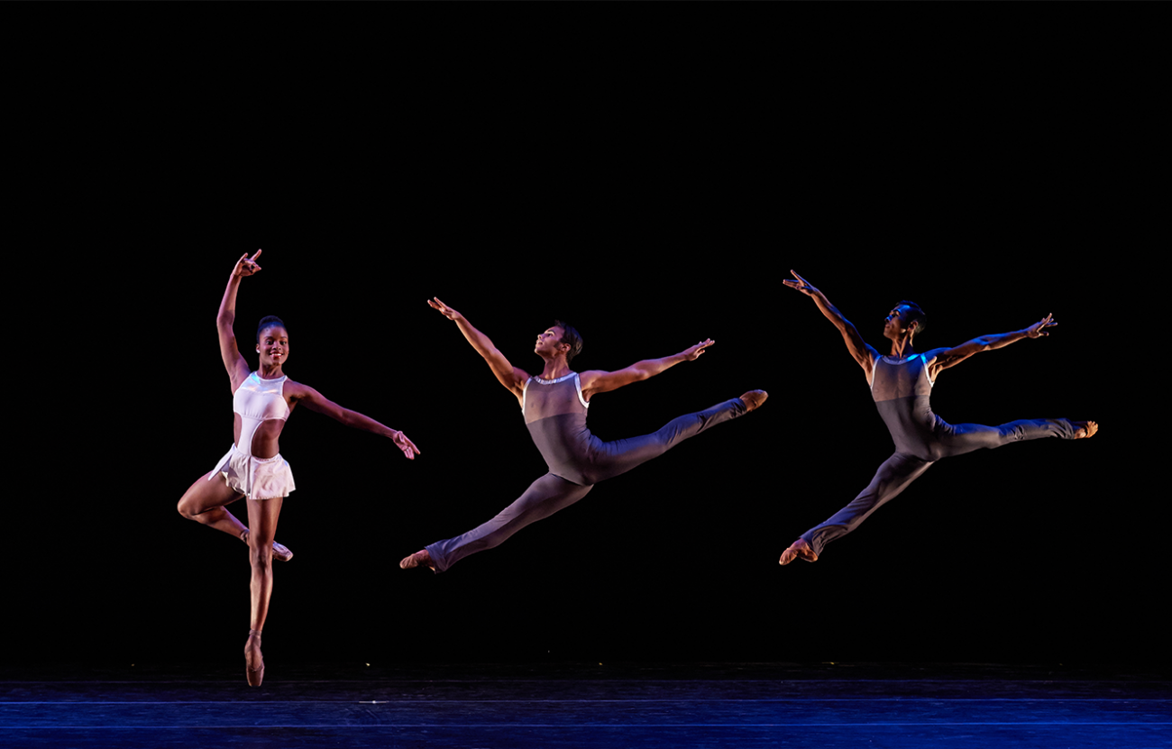 three ballet dancers in mid air during a performance