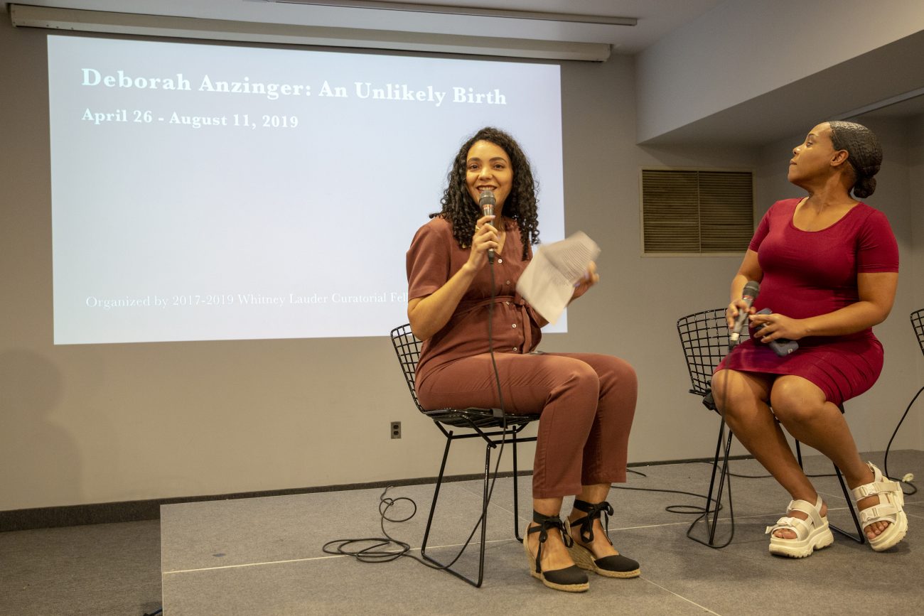 two women on stage speaking to a crowd
