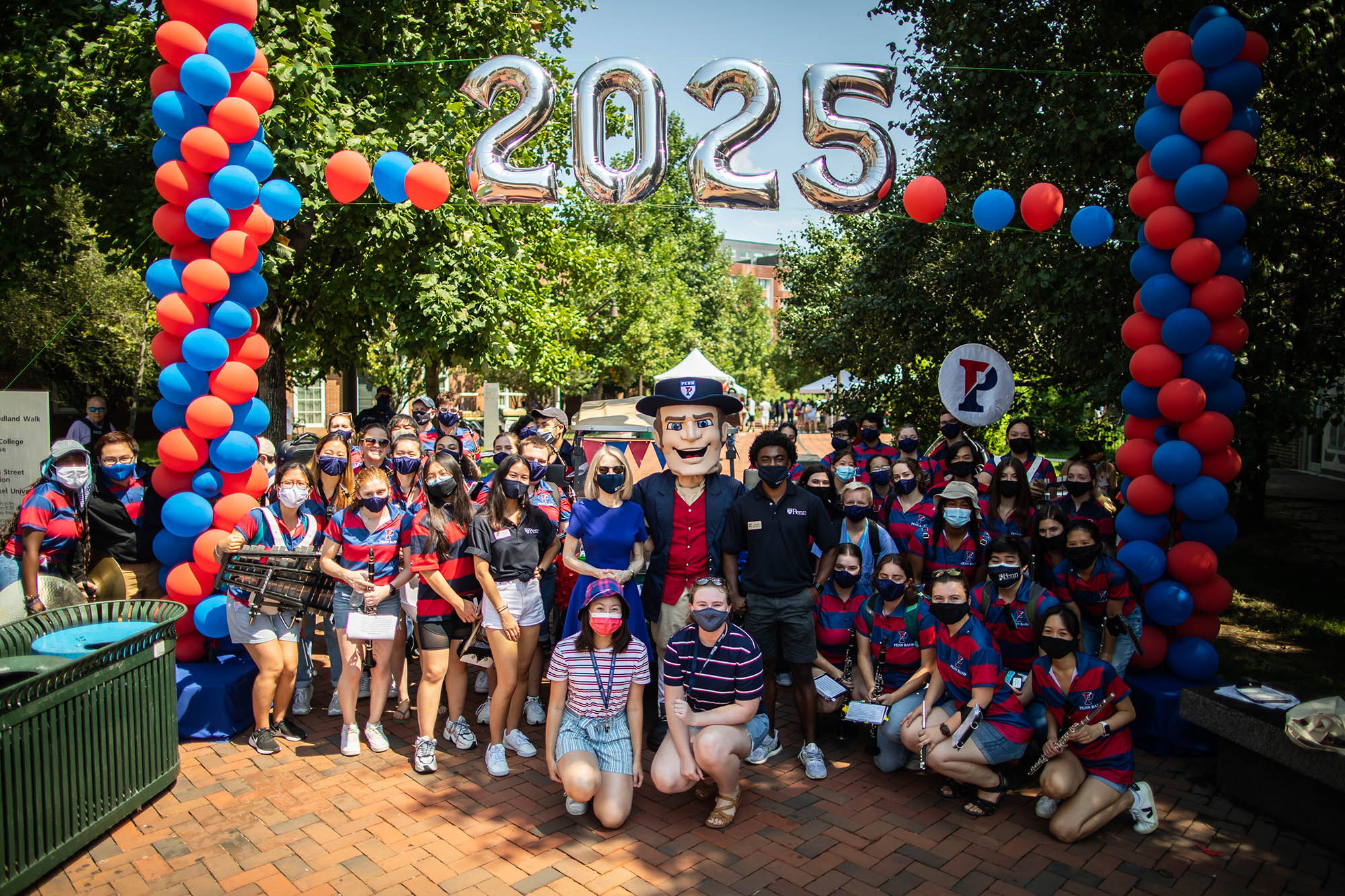President Amy Gutmann poses with the Penn Quaker and the Penn Band outside of Lauder College House