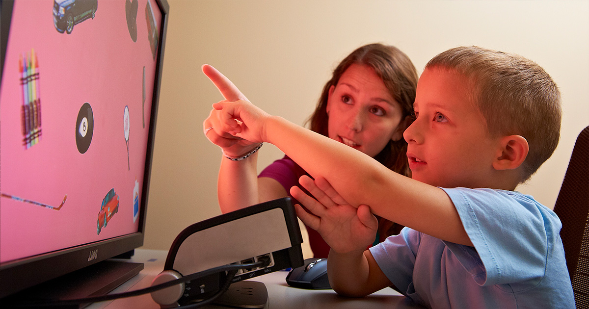 A young student points at pictures on a screen.