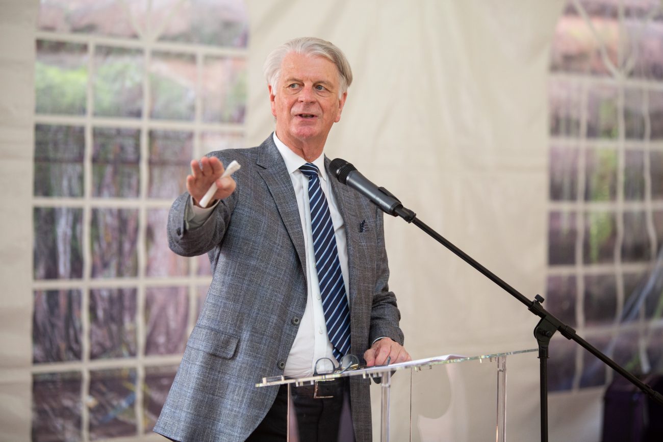 man giving a speech at a glass podium