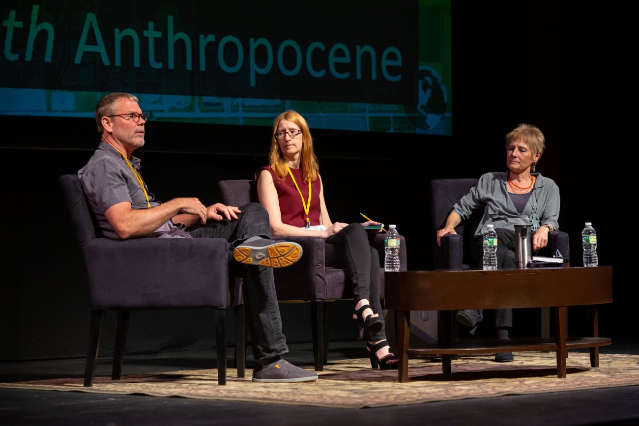 three people sitting in chairs with a coffee table in front of them on stage for a conference