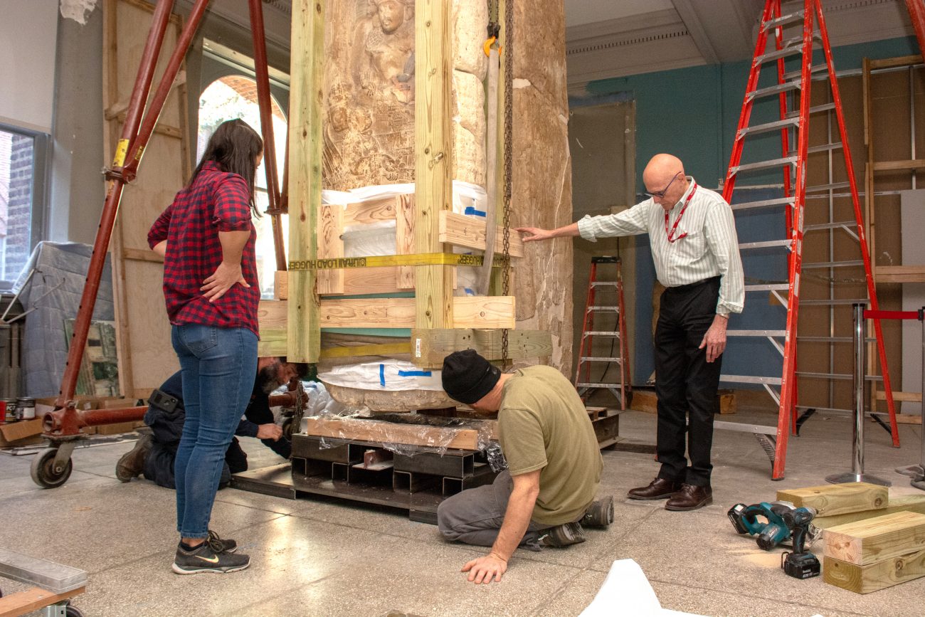 Museum staff and technicians guide the monument onto its new support structure.