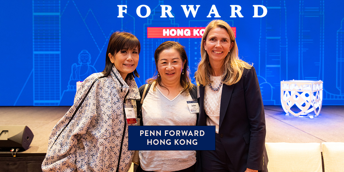 Three attendees at Penn Forward Hong Kong pose together in front of the event stage