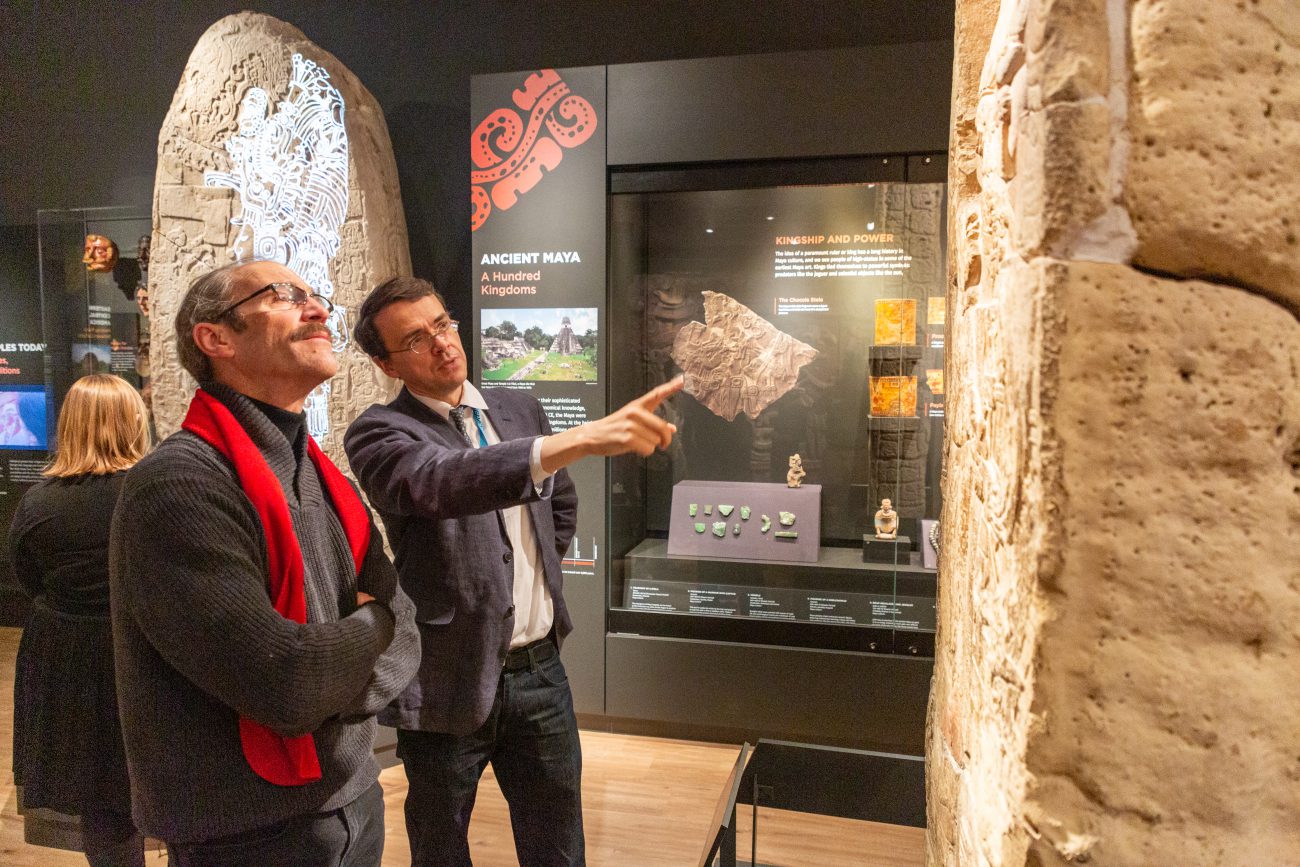 Simon Martin (at right), lead curator of the Mexico and Central America Gallery, speaks with a visitor about one of several Maya stelae on display.