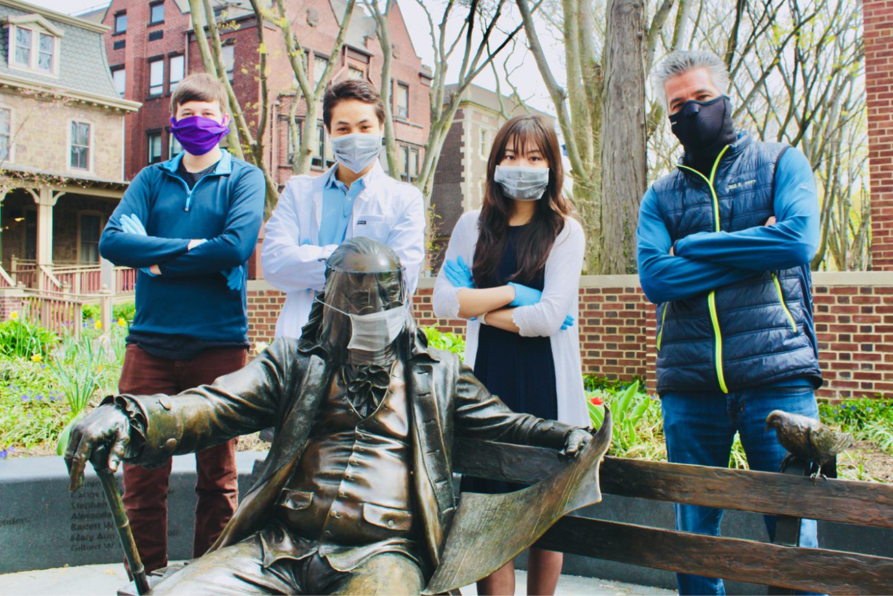 Students in masks behind ben franklin statue in mask