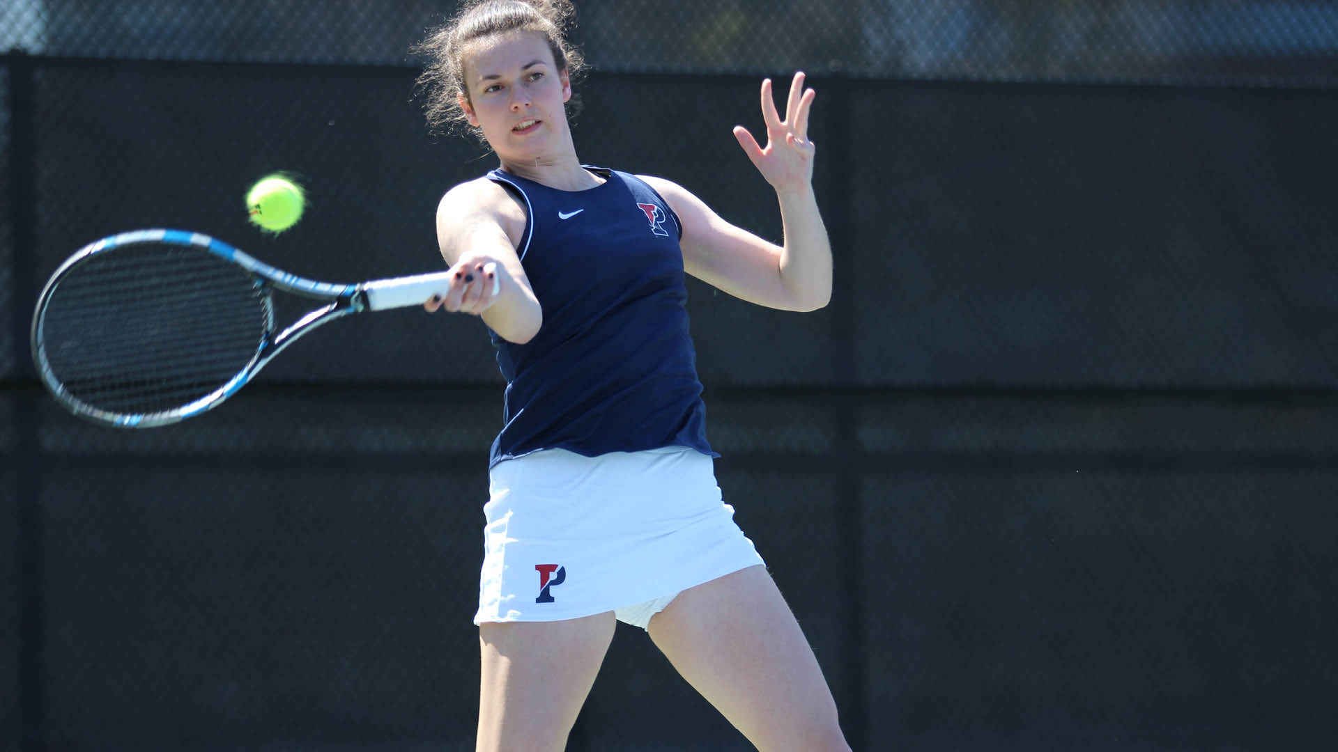 A Penn women's tennis player returns a ball during a game.