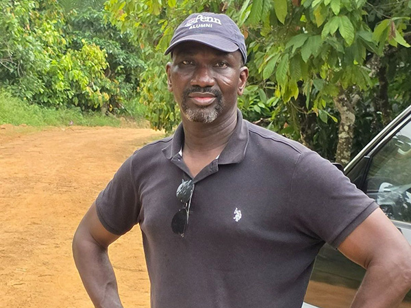 Robert Asante, GRD'19, stands with his hands on his hips in a lush outdoor setting.
