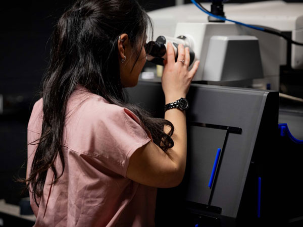 Researcher using a microscope in the Center for Innovation and Precision Dentistry lab.