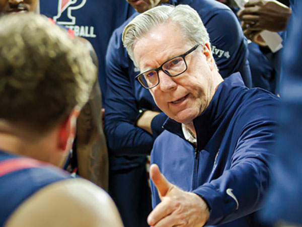 Penn men's basketball coach Fran McCaffery, W’82, speaks with one of his players during a meeting on the court.