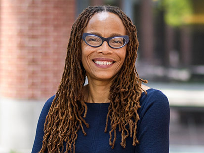 A portrait of Dorothy Roberts, smiling broadly in the Penn Carey Law courtyard.