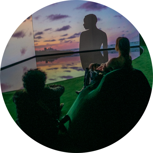 Two audience members, shown in silhouette, experience an immersive environment in Terence Nance's 