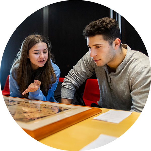 Two students converse while studying a rare document from the Penn Libraries' collection