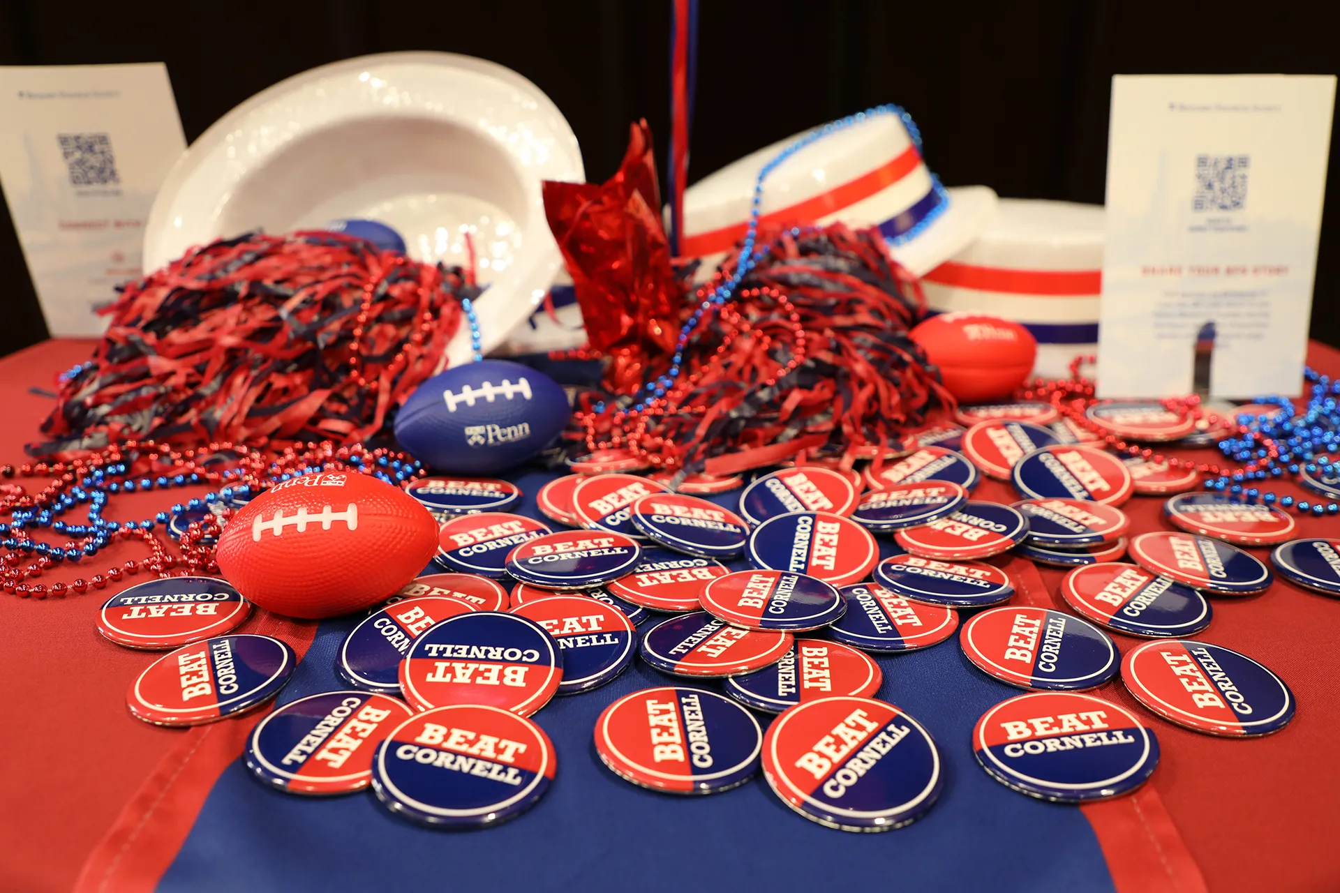 Close-up of Penn-themed table with 'Beat Cornell' buttons and cheer gear