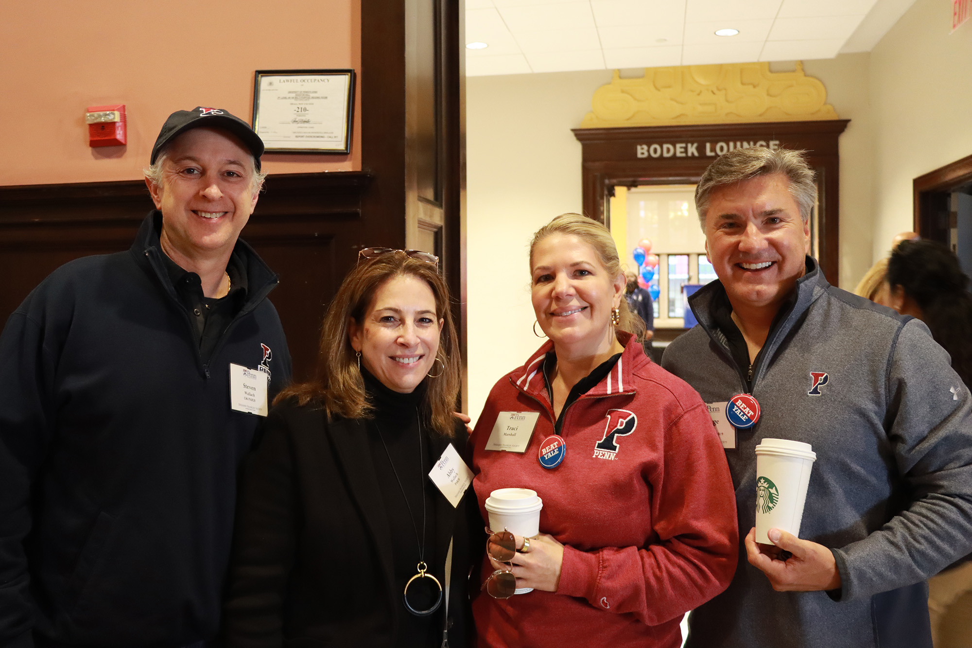 A group of four Penn alumni smile for the camera during the 2022 Homecoming Brunch for members of the Benjamin Franklin Society at the University of Pennsylvania.