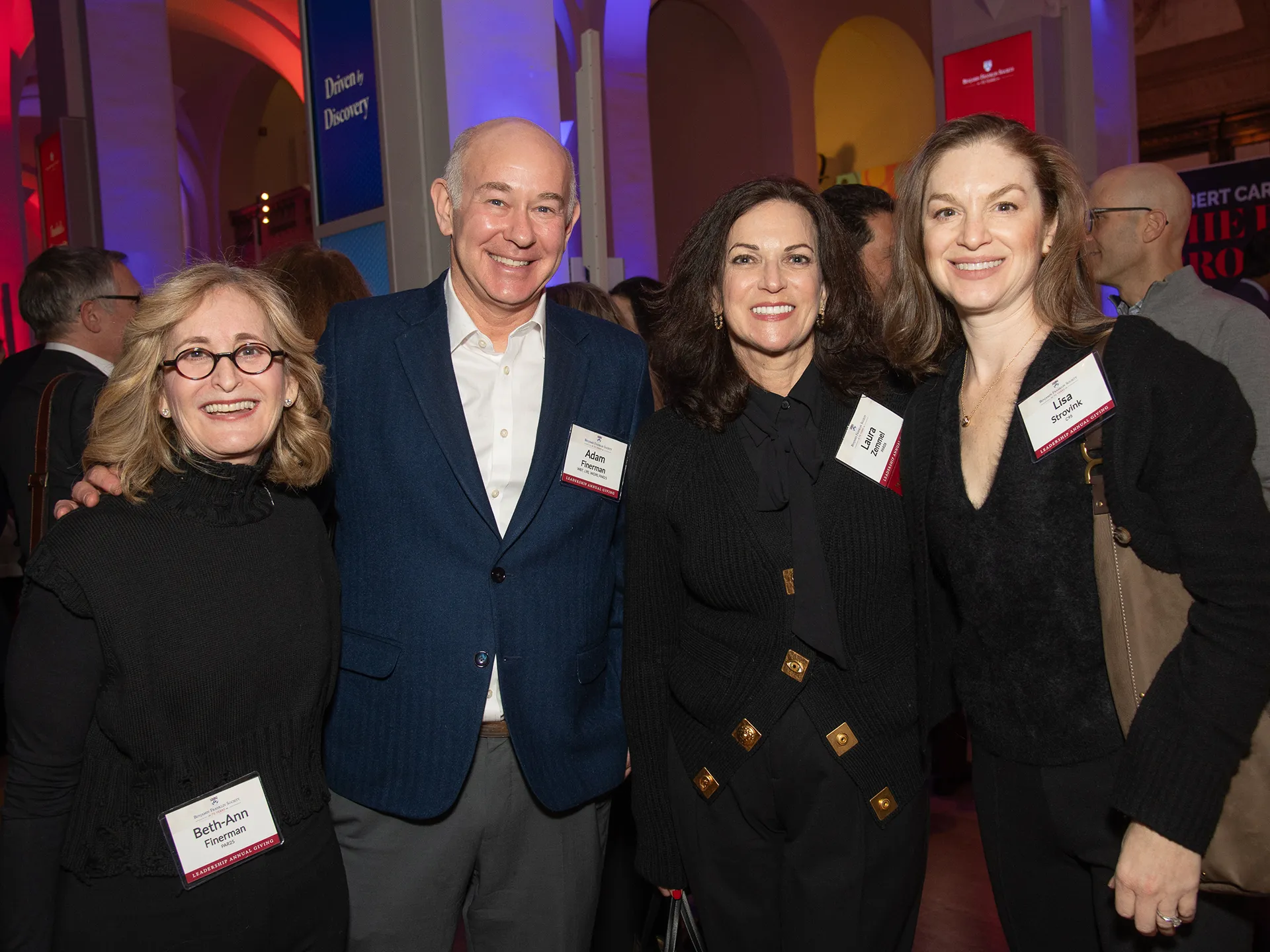 BFS attendees smile for a group photo at the 70th Anniversary Spring Reception, surrounded by Penn-themed banners and fellow guests.