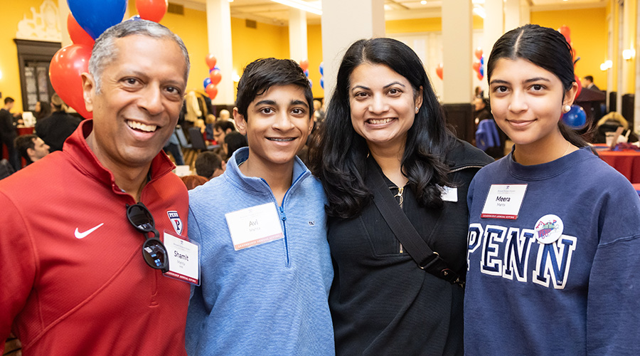 A vibrant family portrait featuring a father in a red Penn shirt and his family, including two teenage children, all with bright smiles, at the 2024 Benjamin Franklin Society Brunch.