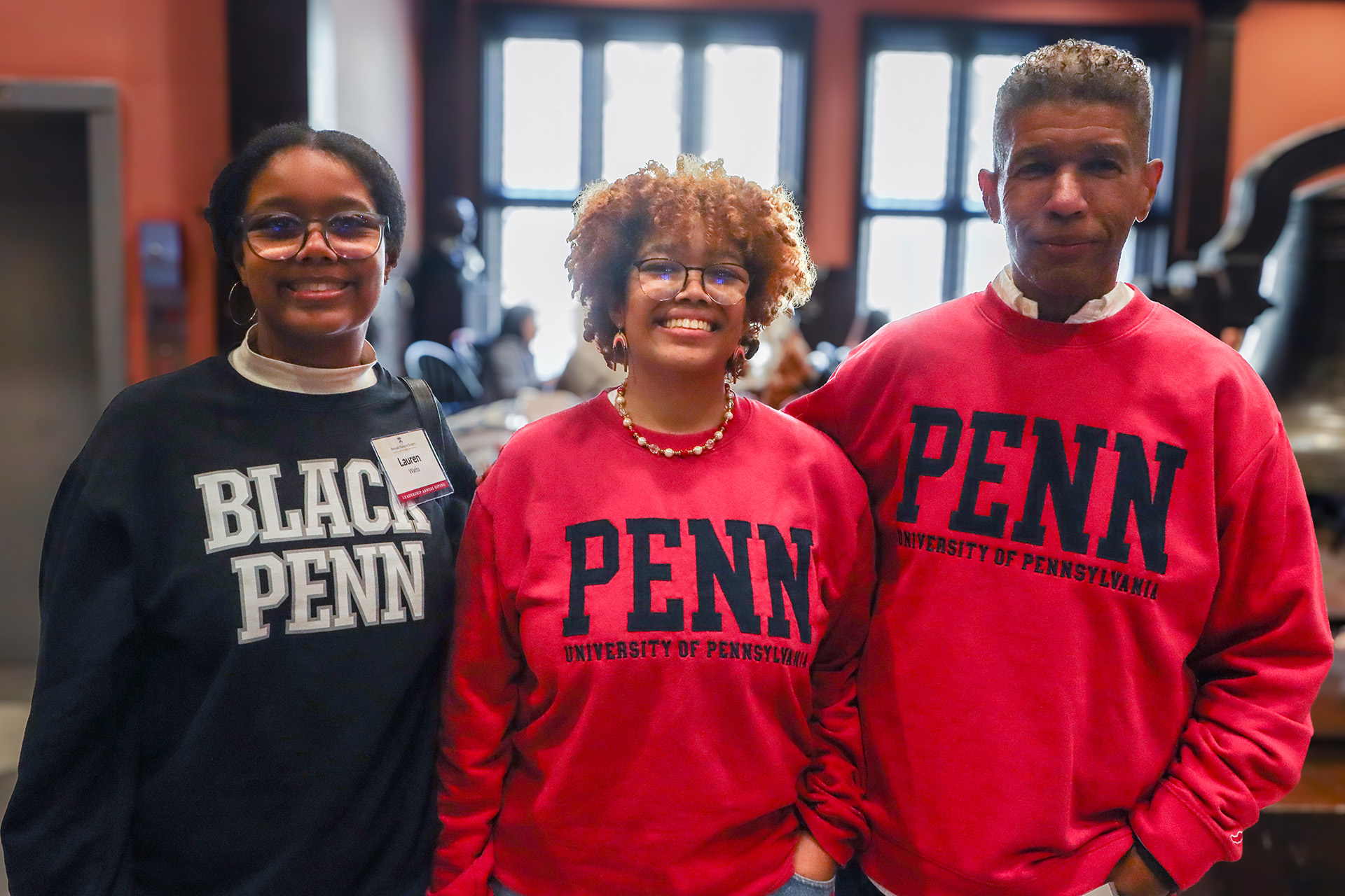 A family of three poses for a photo at the 2024 Benjamin Franklin Society Brunch. The parents wear matching 