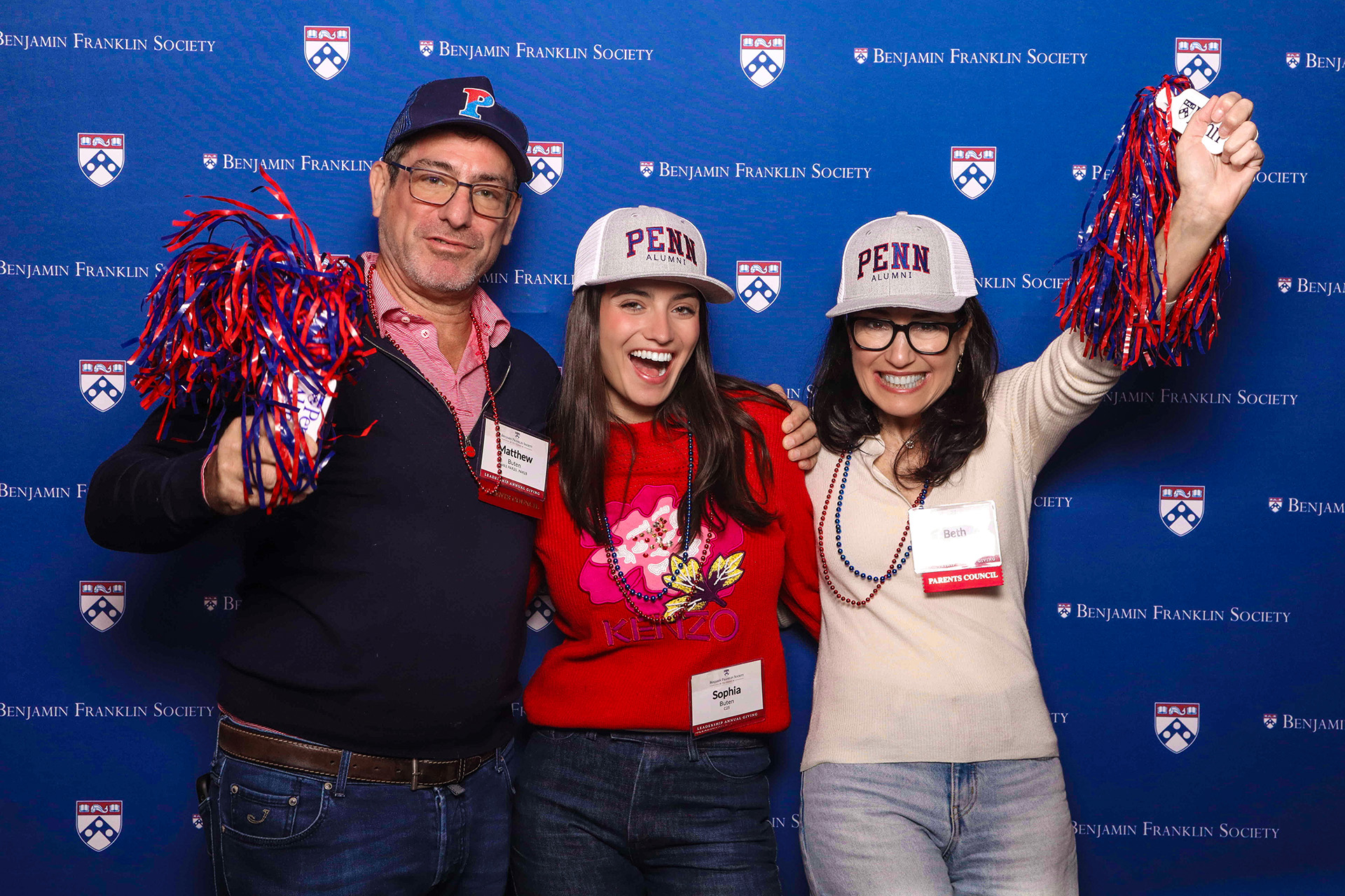 A family of three pose in front of the step and repeat setup at the 2024 Benjamin Franklin Society Brunch.