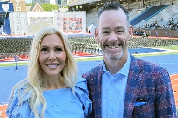 Tracy and Cameron Falconer, PAR'25, PAR'27, co-chairs of the Penn Parents Council, smiling together as they stand in the bleachers at Franklin Field.