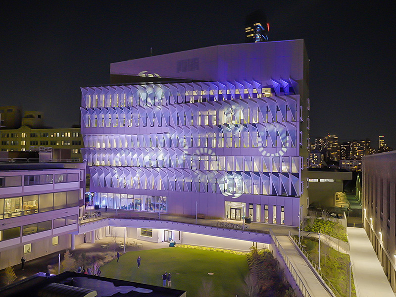 The Vagelos Laboratory for Energy Science and Technology pictured at night, illuminated in blue, purple, and white lights.
