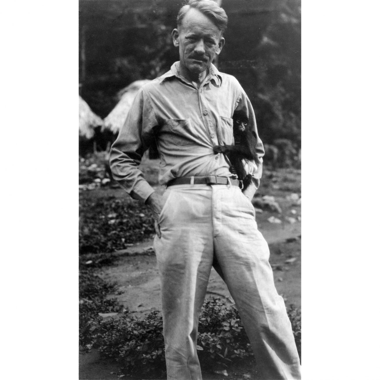 a man standing with a monkey holding on to his waist Piedras Negras, Guatemala in 1932.