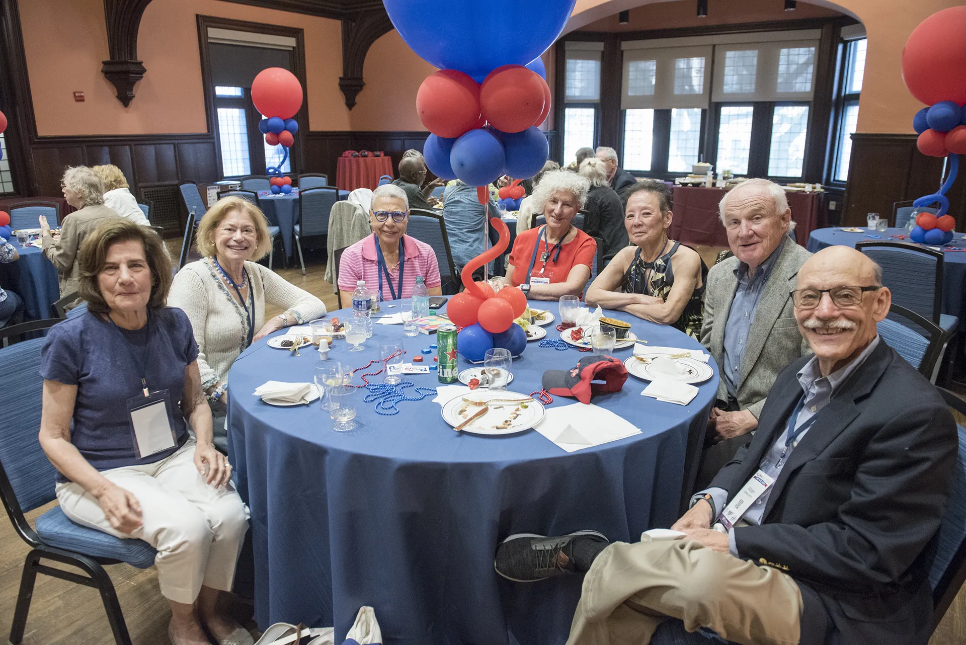 University of Pennsylvania Class of 1970 alumni seated around a table adorned with red and blue balloon centerpieces enjoying a luncheon during their 55th reunion celebration