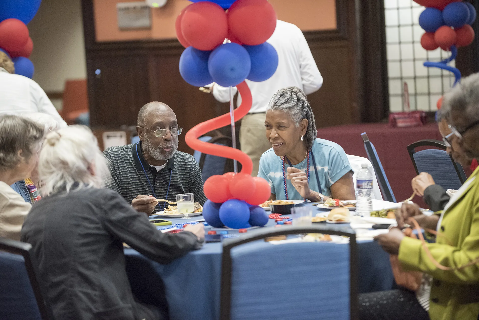 University of Pennsylvania Class of 1970 alumni chatting and dining around a table with red and blue balloon centerpiece during their 55th reunion