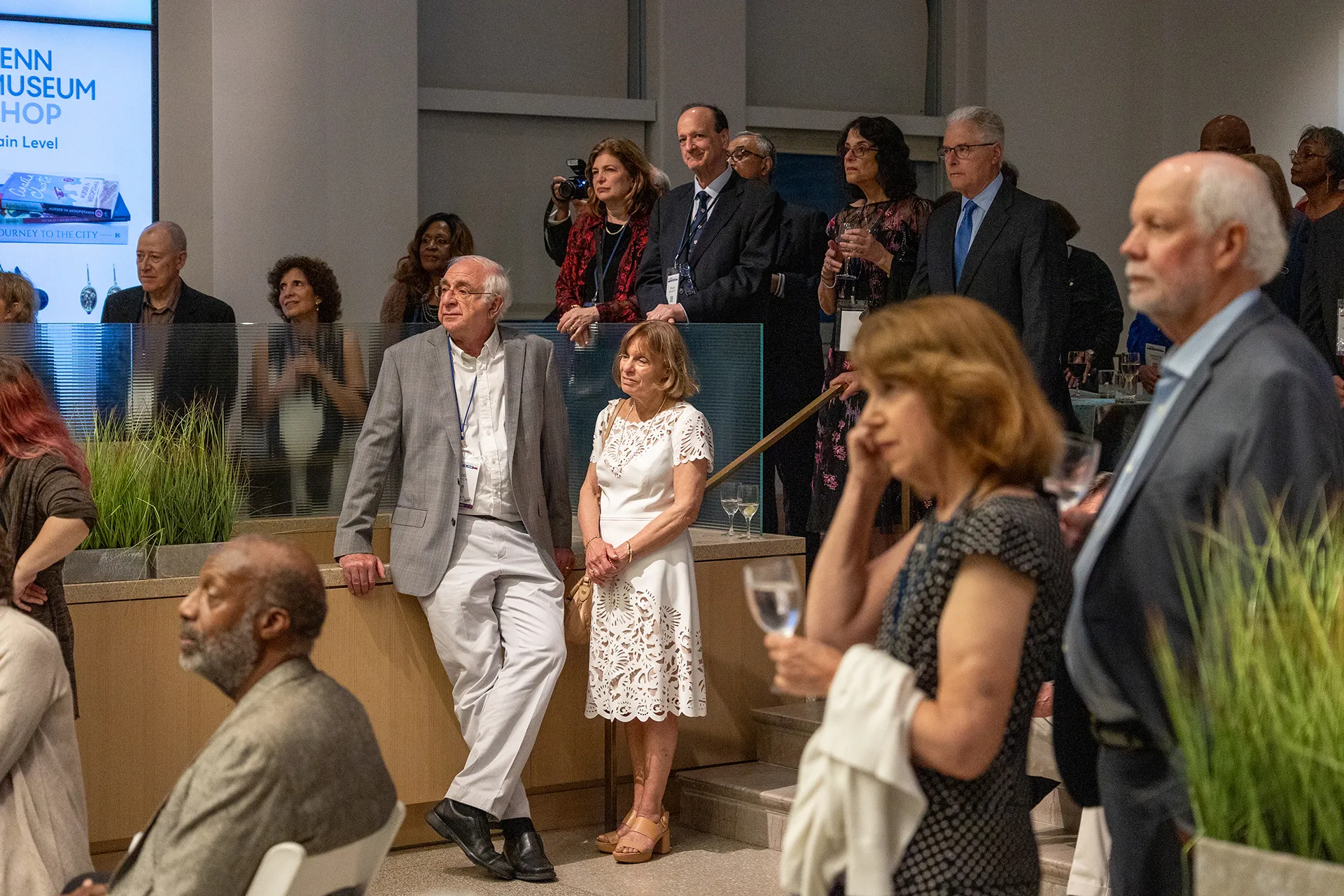 University of Pennsylvania Class of 1975 alumni standing and listening together in the Penn Museum lobby during their 50th reunion celebration