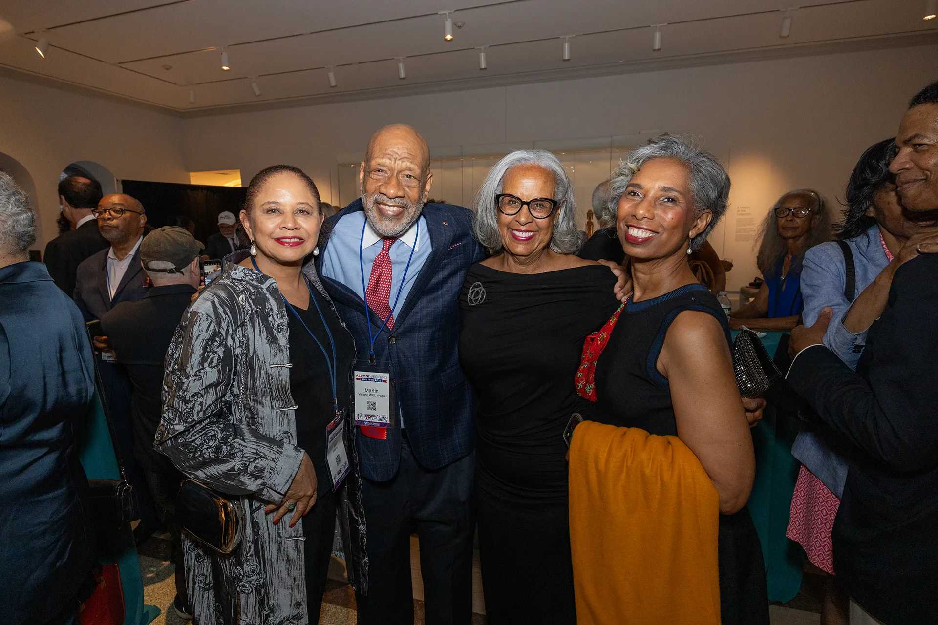 Four University of Pennsylvania Class of 1975 alumni smiling together at their 50th reunion reception in an art gallery setting