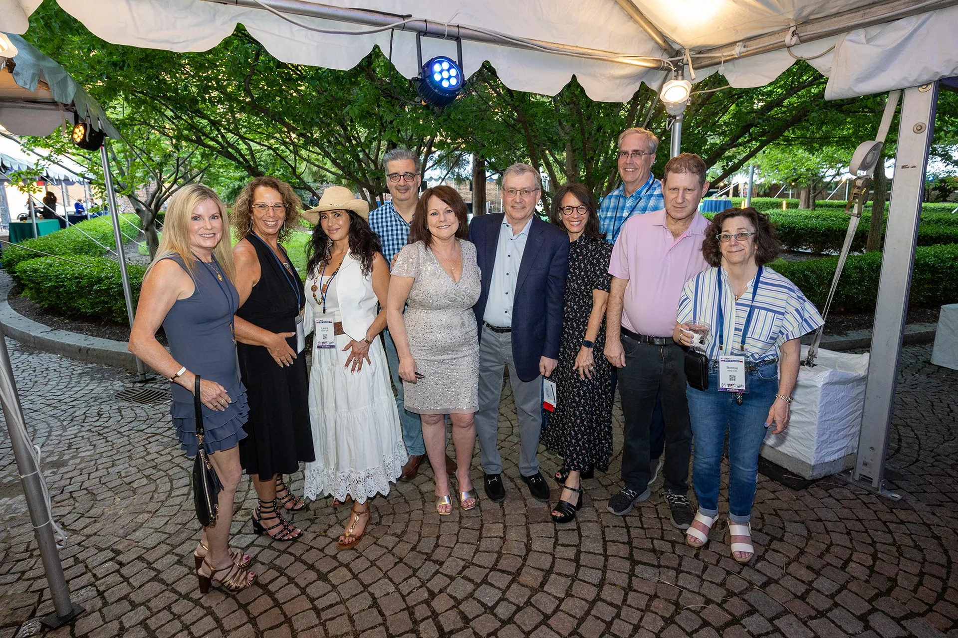 University of Pennsylvania Class of 1985 alumni standing together under a white tent on a cobblestone courtyard at their 40th reunion