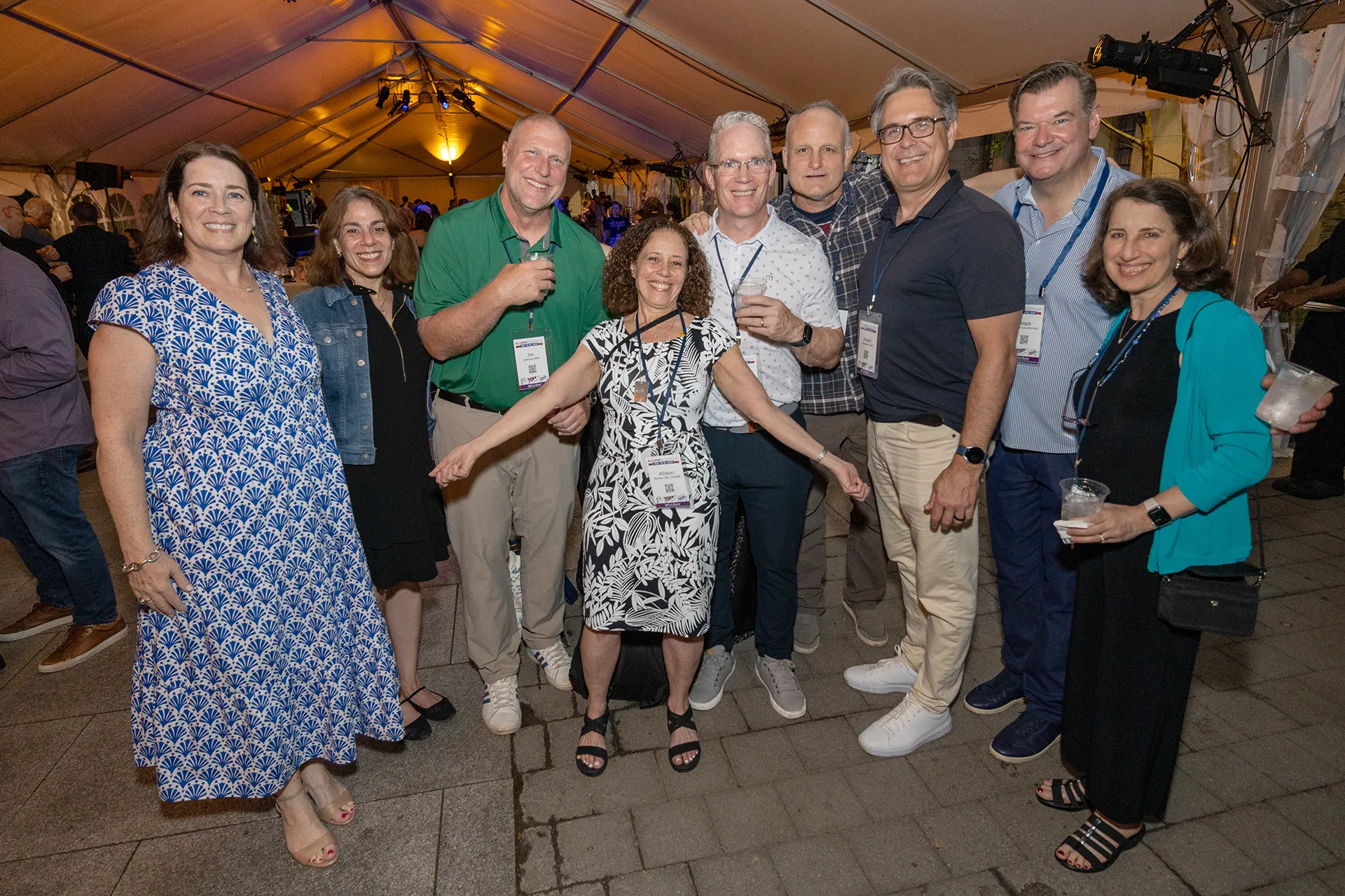 University of Pennsylvania Class of 1990 alumni and alumnae standing together under a large white tent, holding drinks and name badges at their 35th reunion