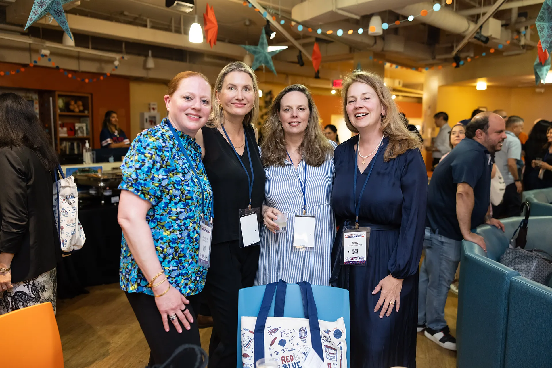 Group portrait of four Penn Class of 1995 graduates standing under star garlands in a festive photo-booth area at their 30th reunion