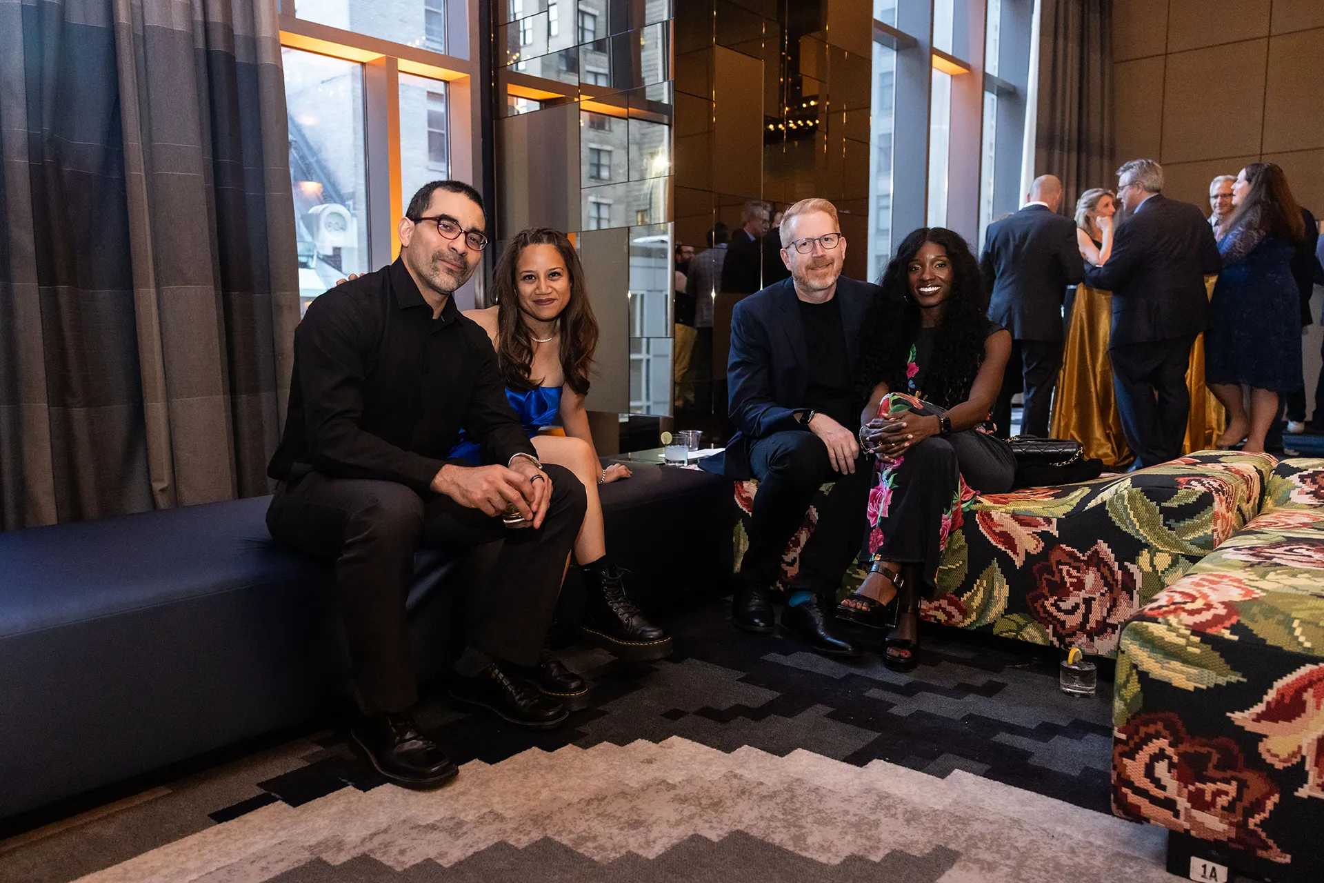 Four University of Pennsylvania alumni from the Class of 2000 seated on patterned lounge benches with cocktails at their 25th Reunion reception