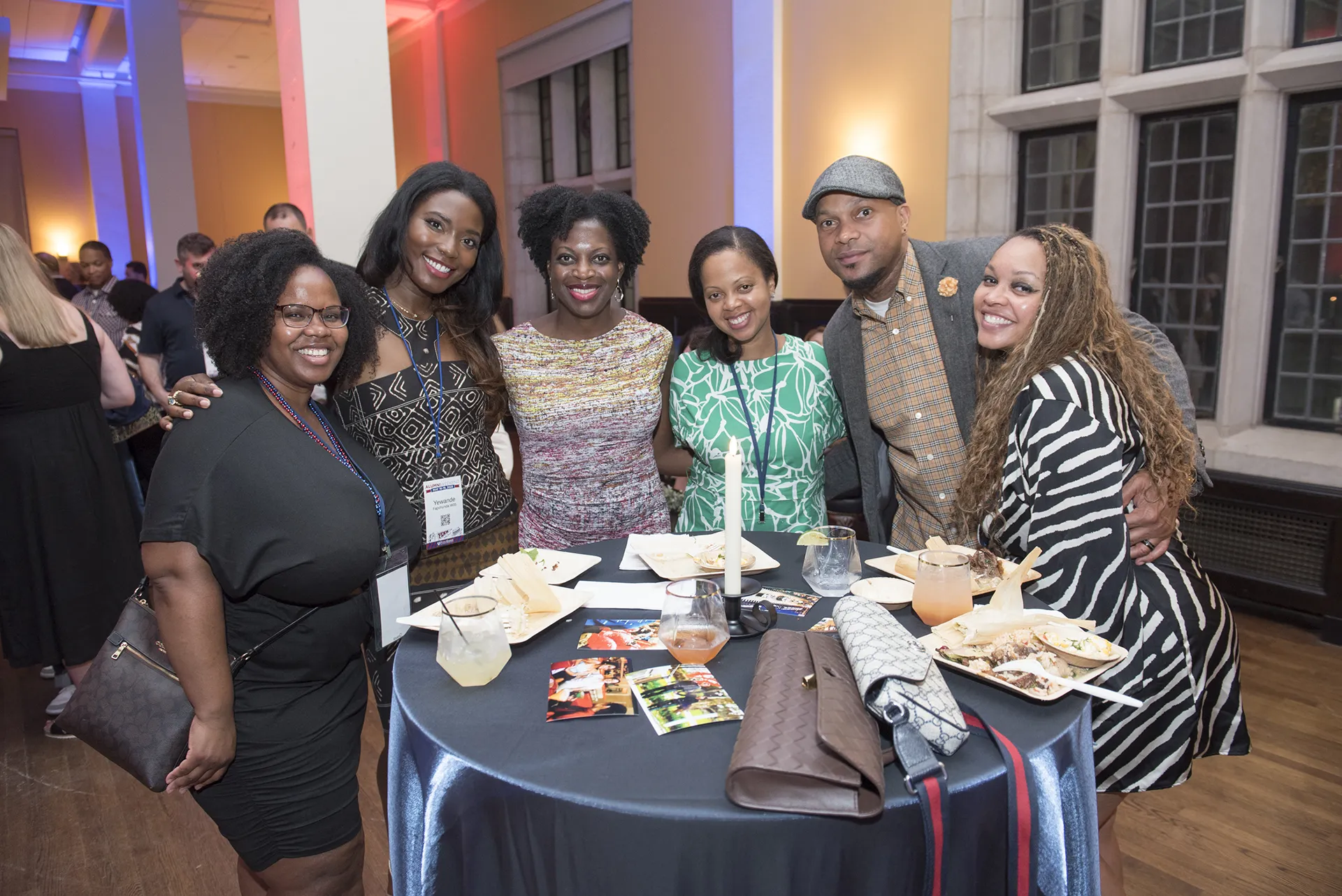 Six Class of 2005 alumni from the University of Pennsylvania standing around a cocktail table with appetizers and drinks at their 20th Reunion celebration