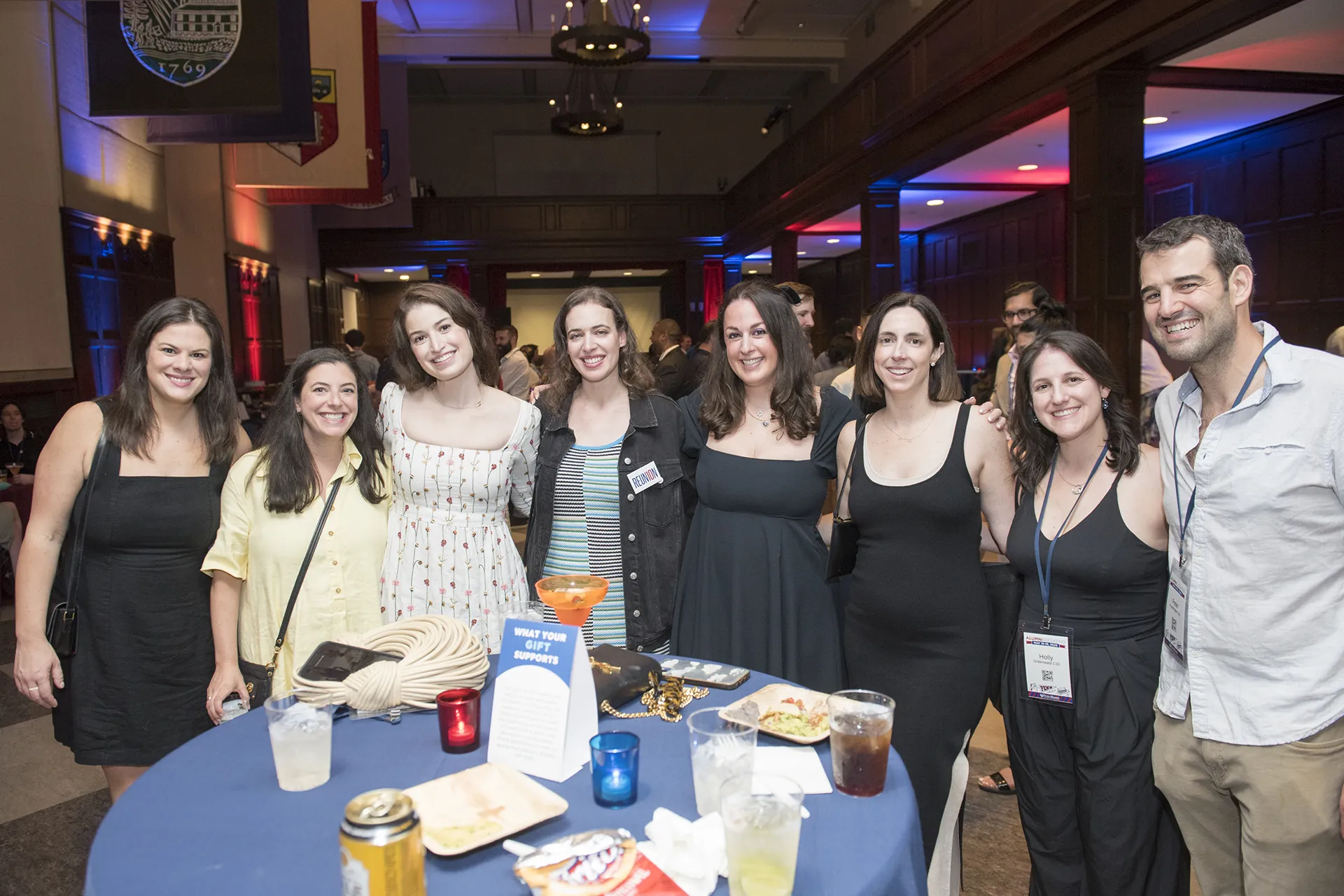 University of Pennsylvania Class of 2010 alumni gathered around a cocktail table at their 15th Reunion event, smiling and holding drinks