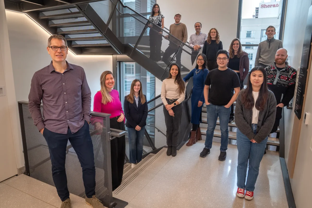 Duncan Watts stands with members of the CSSLab team on a staircase inside a Penn research building.