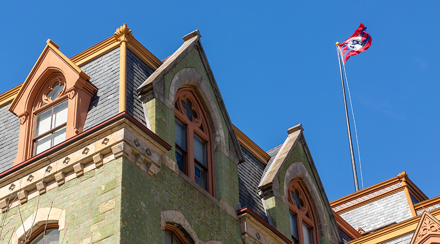 The school flag waving in the wind atop College Hall on a clear day at the University of Pennsylvania.