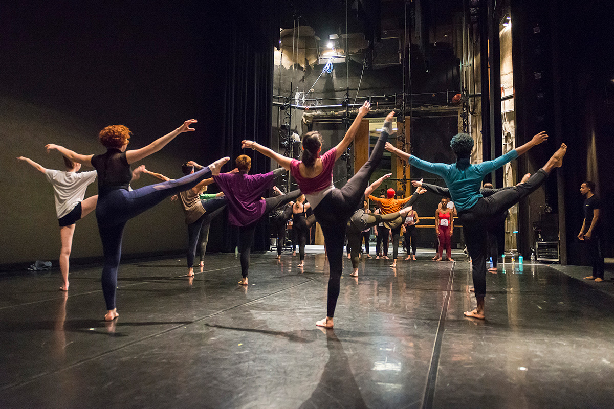 A group of Penn students practice a dance routine on a stage.