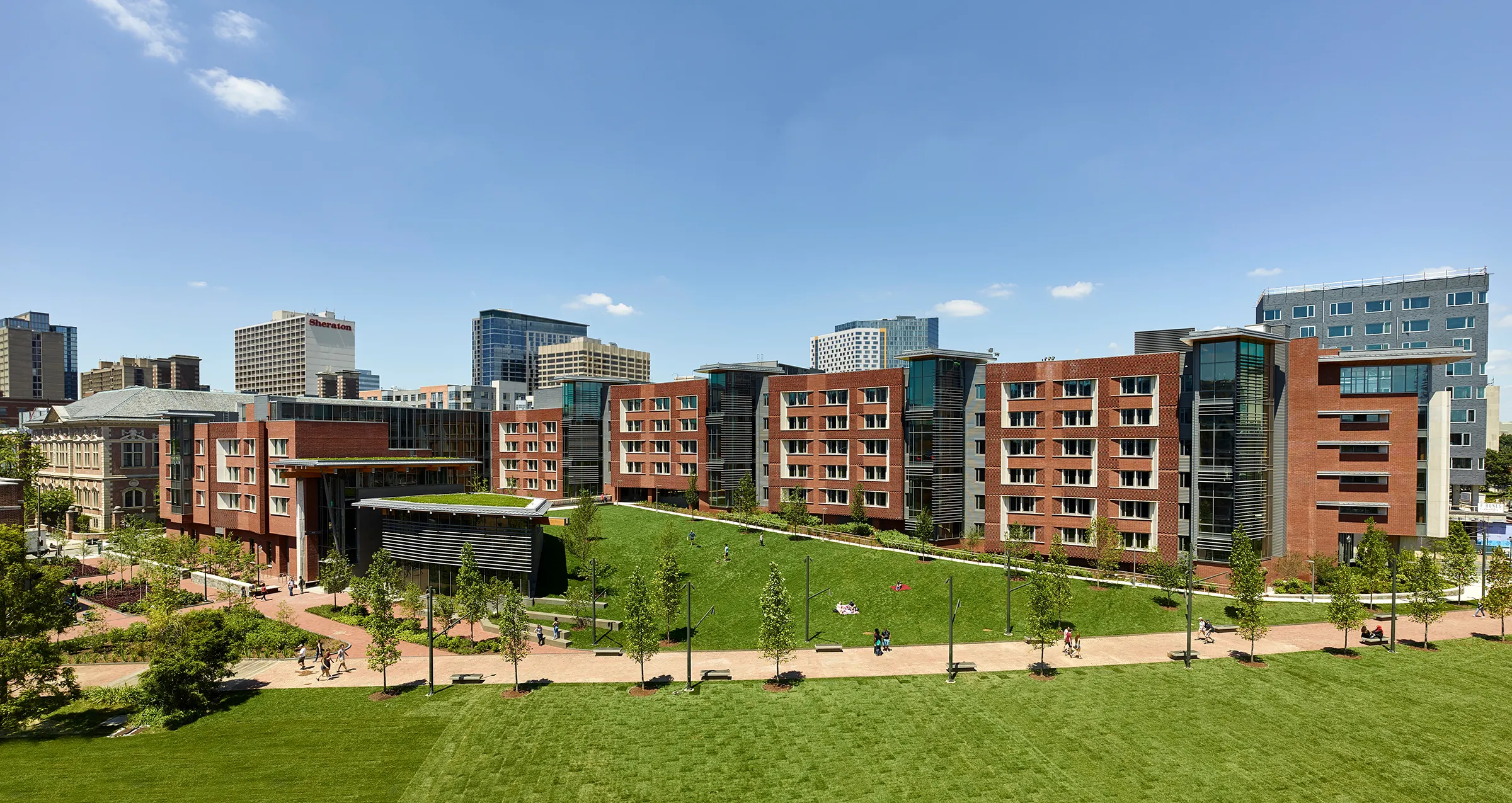 Lauder College House at Penn with green space and students walking on a sunny day.