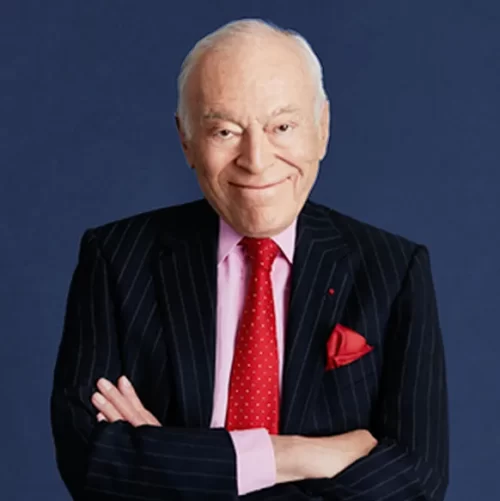 Portrait of Leonard Lauder wearing a suit and smiling with arms crossed.