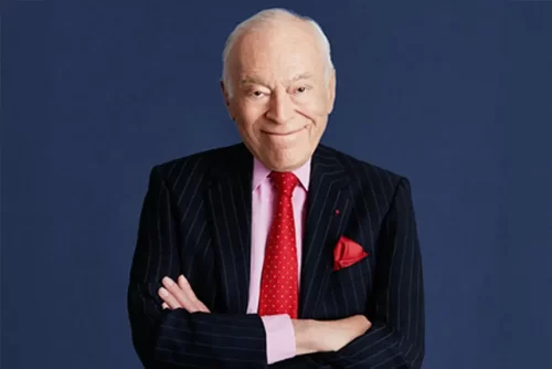 Portrait of Leonard Lauder wearing a suit and smiling with arms crossed.