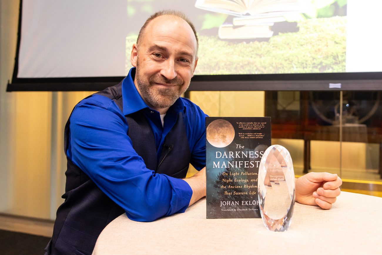 Johan Eklöf poses with a copy of his book, "The Darkness Manifesto," and the crystalline trophy awarded for the Penn Libraries’ Sustainability Book Prize.