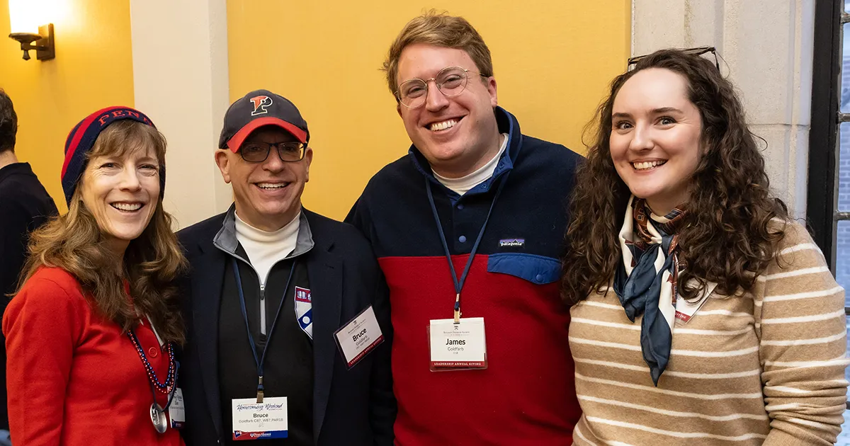 A group of loyal Penn Fund donors smile together at an indoor alumni gathering, celebrating their continued support for undergraduate initiatives.