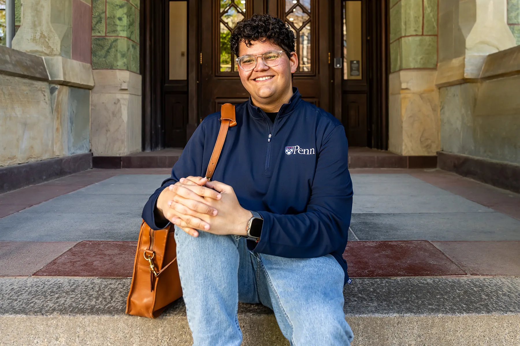 University of Pennsylvania student Noah Milad seated on College Hall steps with a smile