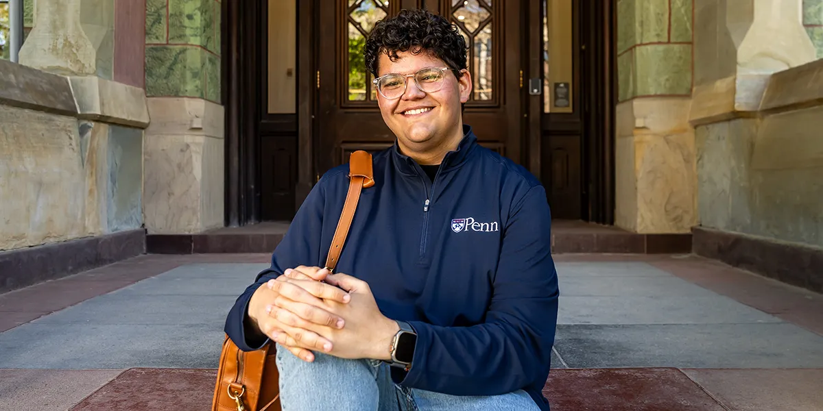 University of Pennsylvania student Noah Milad seated on College Hall steps with a smile
